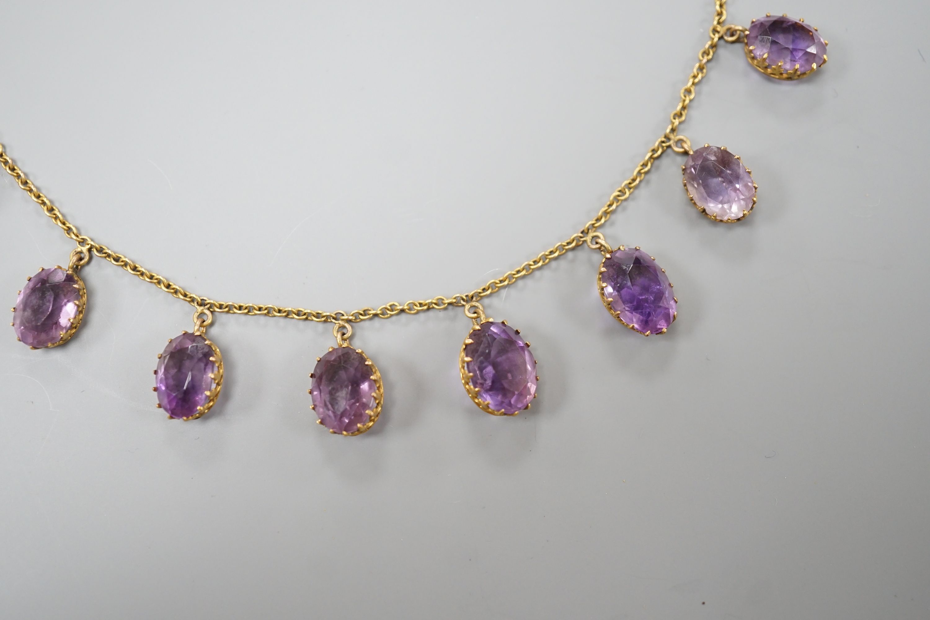 An early 20th century 9ct and graduated oval cut amethyst set drop fringe necklace, 45cm, gross weight 11.8 grams.